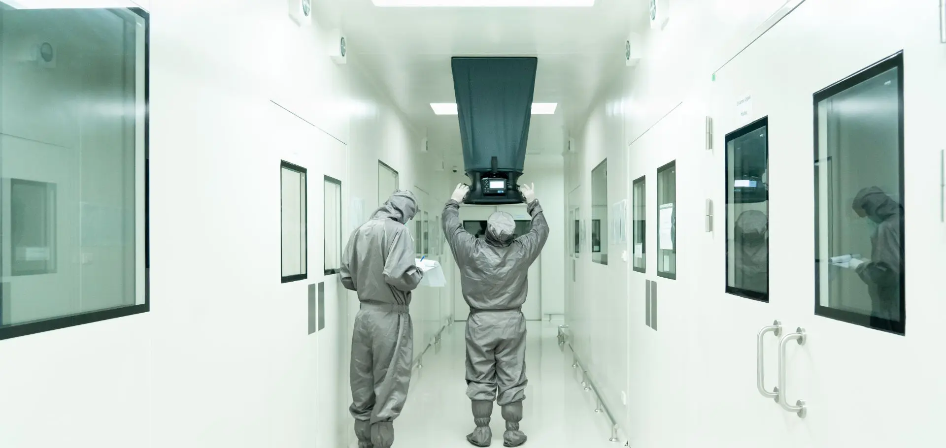 Two men in grey suits are working inside a building.