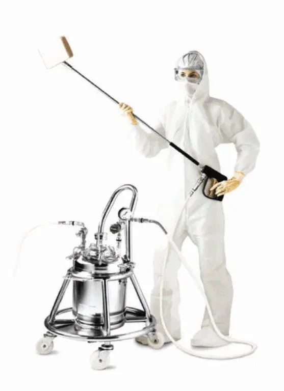 A man in white suit holding a mop next to a machine.