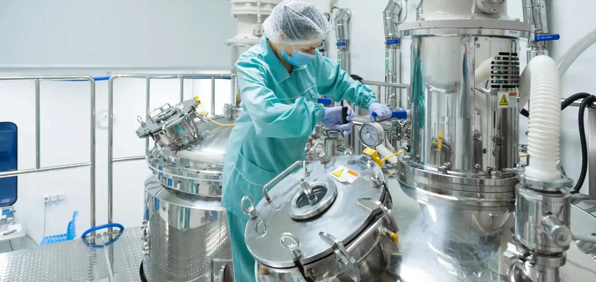 A person in blue lab coat and gloves working on machinery.