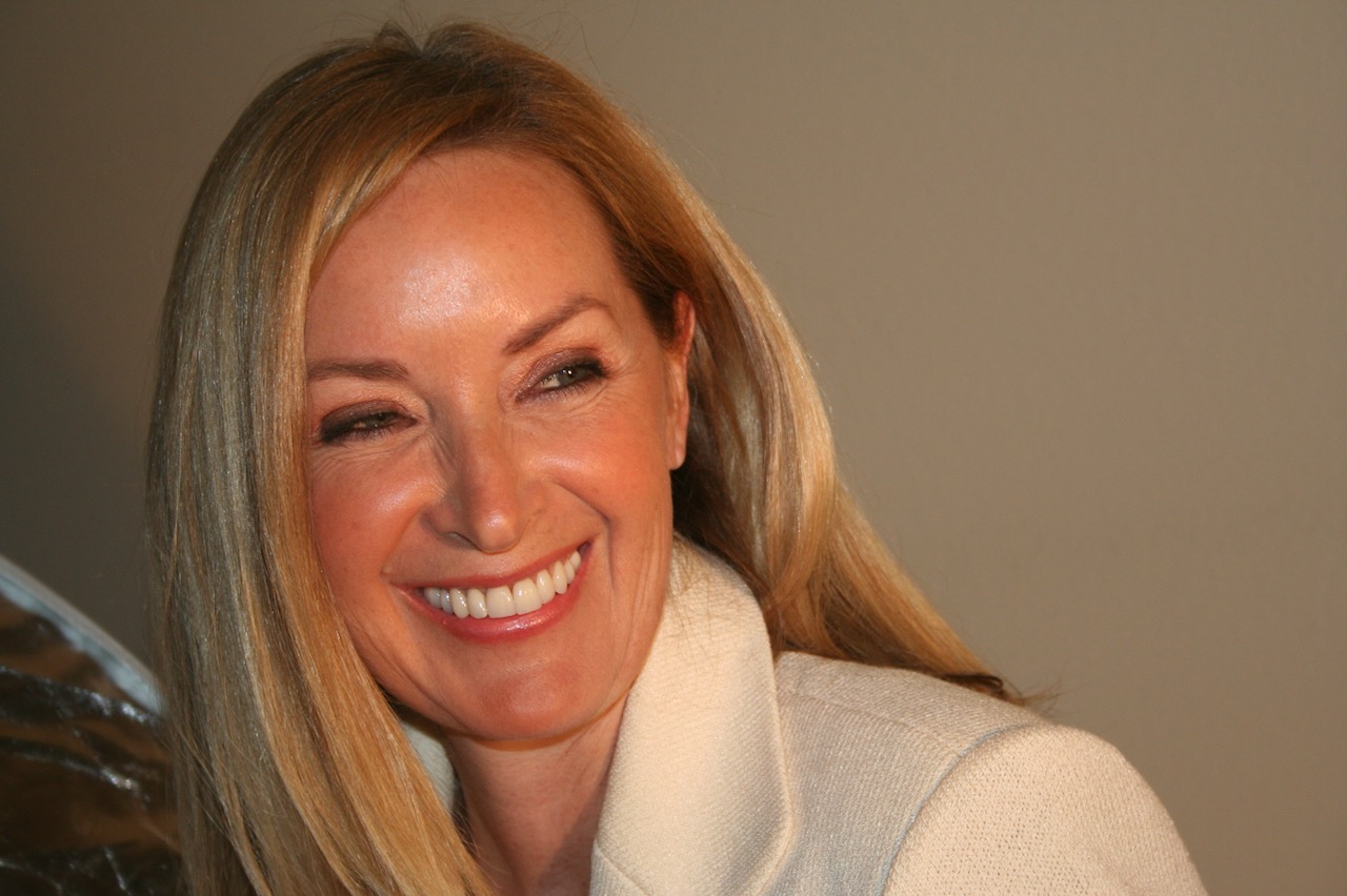 A woman smiling with long blonde hair.