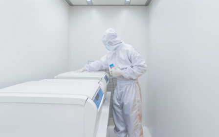 A person in white suit standing next to a refrigerator.