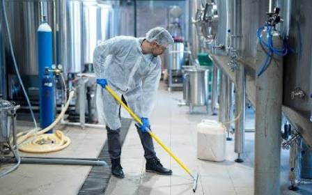 Worker mopping industrial factory floor.